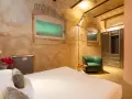 Camera accogliente con letto, poltrona verde e armadio. Un tocco di lusso, come un boscolo circo massimo, per un soggiorno indimenticabile.