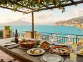 Un tavolo apparecchiato con piatti tipici sorrento, pizza, frittura e burrata, con vista sul golfo.