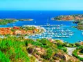 Vista panoramica di Porto Cervo con il suo porto turistico pieno di yacht e le case colorate che si affacciano sul mare cristallino. Un luogo da sogno per scoprire cosa vedere a Porto Cervo.