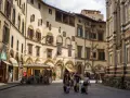 Un gruppo di turisti con valigie a rotelle cammina in una piazza fiorentina, un'immagine perfetta per un **viaggio in Toscana**.