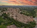Panoramica aerea di San Gimignano, con le sue torri medievali che svettano tra i tetti rossi. Un sogno di **Volterra e San Gimignano in un giorno**.