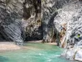 Acque cristalline scorrono tra le imponenti pareti basaltiche delle gole dell'Alcantara, creando una spiaggia naturale suggestiva.