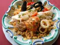 Piatto di pesce misto con couscous: ecco cosa mangiare a Trapani. Gamberi, calamari, pesce bianco e cozze.