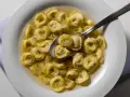 Tortellini in brodo, uno dei piatti tipici di Ravenna, serviti in una ciotola bianca con un cucchiaio.