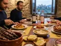 Un gruppo di amici gusta la gastronomia abruzzese: arrosticini, pasta al ragù, fritti e pesce.