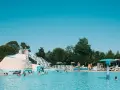 Bambini e adulti si divertono nella piscina del villaggio Ca' Laguna, con scivoli e zone relax sotto il sole.