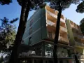 Edificio del pine beach hotel rosolina mare, con balconi e alberi di pino davanti.