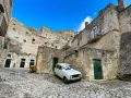 Un'auto d'epoca bianca in un vicolo di Matera, perfetta per visitare la città in un giorno.