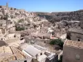 Panoramica dei Sassi di Matera, un **itinerario** suggestivo tra antiche case scavate nella roccia e tetti in cotto sotto un cielo azzurro.