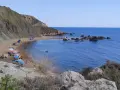 Spiaggia di Cala Vincenzina con scogliere, ombrelloni colorati e bagnanti che si godono il mare azzurro.