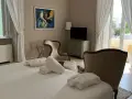 Camera accogliente al relais Corte degli Aragonesi, con letto, accappatoi, poltrone e vista su un balcone fiorito.