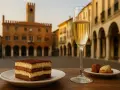 Un delizioso tiramisù e un bicchiere di spumante, perfetti per scoprire cosa mangiare a Treviso, con la piazza sullo sfondo.
