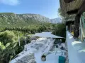 Terrazza panoramica con vista sui monti di Oliena, Sardegna. Arredamento bianco, cactus e vegetazione rigogliosa.