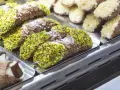 Cannoli siciliani, dolci tipici siciliani, ricoperti di pistacchi e zucchero a velo, in una vetrina.