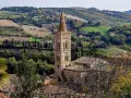 Campanile in borgo marchigiano, tra colline verdi e campi dorati, ideale per itinerari Marche autunnali.