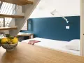 Un letto singolo con lenzuola a righe e un cuscino bianco, sotto una scala in legno e metallo. Un ciotola di limoni sul tavolo crea un'atmosfera da combo Venezia.