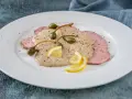 Vitello tonnato, uno dei piatti tipici di Torino, con fettine di carne rosa, salsa cremosa, capperi e limone.