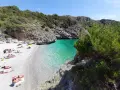 Spiaggia di ciottoli con gente che prende il sole e acque cristalline nel **Cilento mare**.