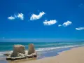 Spiagge bianche in Sicilia, con rocce scolpite dal mare e un cielo azzurro pieno di nuvole bianche.