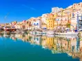 Porto di Sciacca: case colorate a picco sul mare, barche da pesca ormeggiate e riflessi sull'acqua. Un luogo incantevole da scoprire.