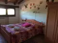 Camera accogliente in un agriturismo al Selvadigo, con letto, coperta colorata, cuscino rosa e decorazioni a farfalle e fiori sul muro.