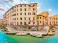 Canali di Livorno, cosa vedere in un giorno: case colorate affacciate sull'acqua, barche ormeggiate e panni stesi al sole.