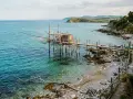 Trabocco tradizionale sulle spiagge dell'Abruzzo, con il mare turchese e la costa rocciosa.