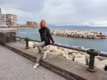 Donna sorridente sul lungomare di Napoli, con Castel dell'Ovo sullo sfondo. Perfetto per scoprire cosa vedere a Napoli in 3 giorni.