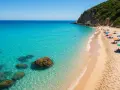 Spiagge del Lazio: sabbia dorata, acque cristalline e ombrelloni colorati sotto una scogliera verdeggiante.
