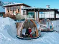 Coppia in una bolla trasparente innevata, perfetta idea su dove andare a gennaio in Italia per un soggiorno da sogno tra le montagne.