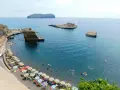 Le **spiagge** di Ventotene, con ombrelloni colorati e bagnanti in un mare azzurro, fanno da cornice a scogli suggestivi e all'isola di Santo Stefano in lontananza.