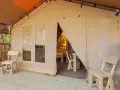 Tenda accogliente nel Luxor Chianti Glamping Village, con sedie in legno sulla veranda e vista sull'interno arredato.