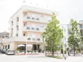 Hotel Atlantic Igea Marina: scopri i prezzi per la tua vacanza al mare. Edificio moderno con alberi verdi davanti.