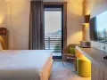 Camera accogliente con vista panoramica, tipica del Linta Hotel Asiago. Letto comodo, poltrona e balcone con paesaggio montano.