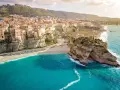 Panoramica mozzafiato delle **calabrie spiagge** con case colorate aggrappate alle scogliere e un mare turchese.