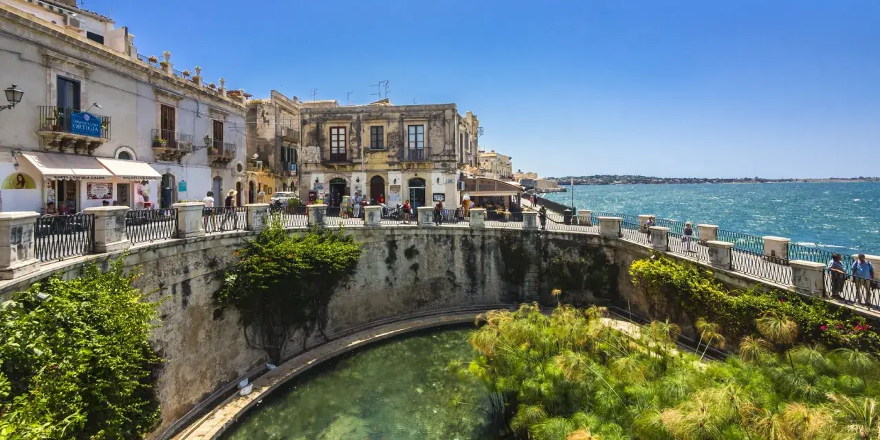 Passeggiata sul lungomare di Ortigia, Siracusa, ideale per un tour sicilia sud orientale 7 giorni. L'acqua cristallina e i papiri incantano.