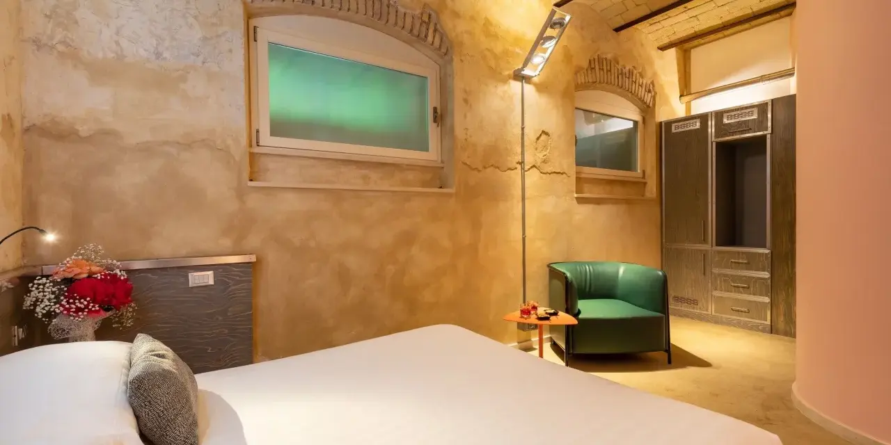Camera accogliente con letto, poltrona verde e armadio. Un tocco di lusso, come un boscolo circo massimo, per un soggiorno indimenticabile.
