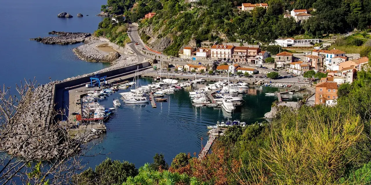 Maratea: un incantevole porto con barche ormeggiate, case colorate e vegetazione lussureggiante. Scopri cosa vedere nel suo centro storico.
