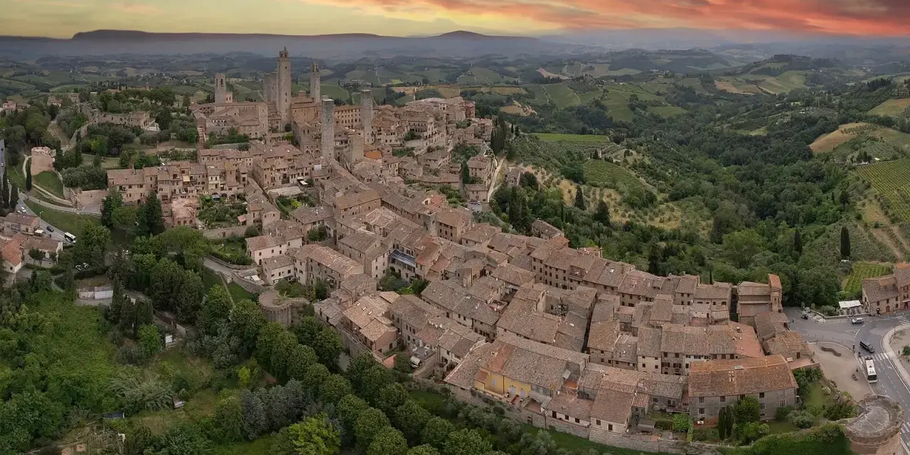 Panoramica aerea di San Gimignano, con le sue torri medievali che svettano tra i tetti rossi. Un sogno di **Volterra e San Gimignano in un giorno**.