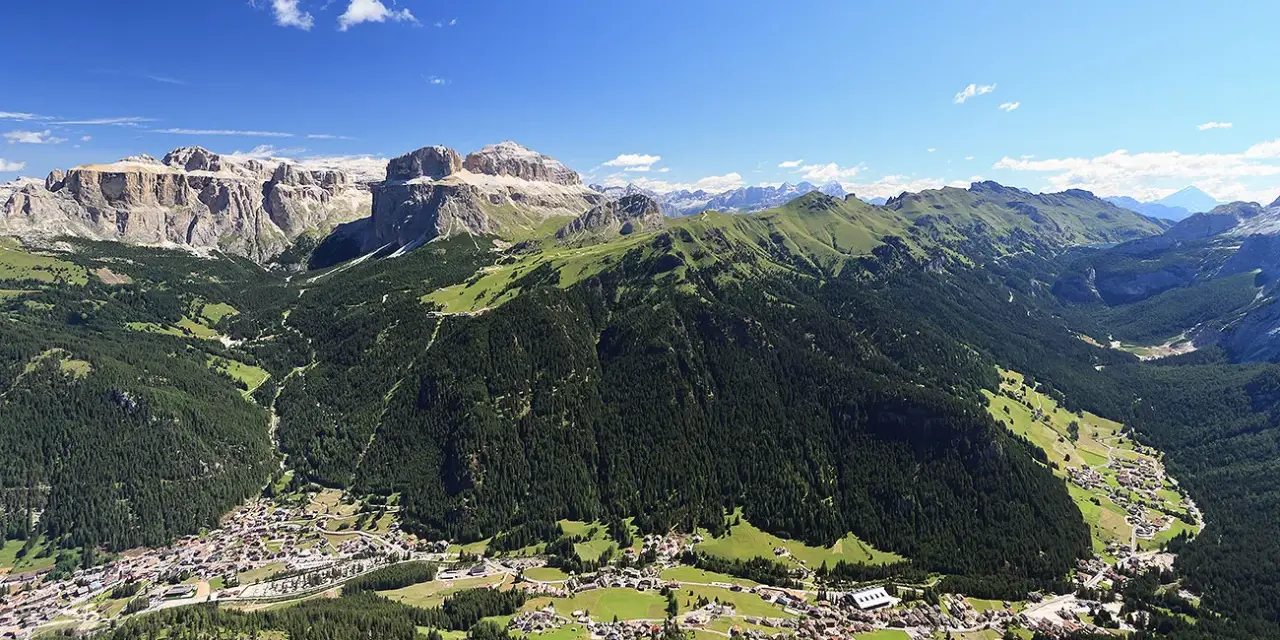 Panoramica delle Dolomiti, ideale per scoprire cosa vedere in Trentino in 3 giorni: valli verdi, boschi fitti e villaggi alpini sotto maestose cime rocciose.