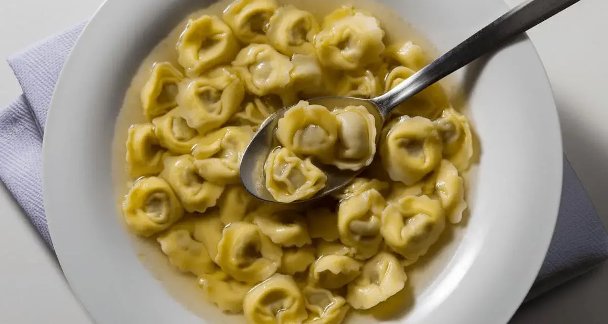 Tortellini in brodo, uno dei piatti tipici di Ravenna, serviti in una ciotola bianca con un cucchiaio.
