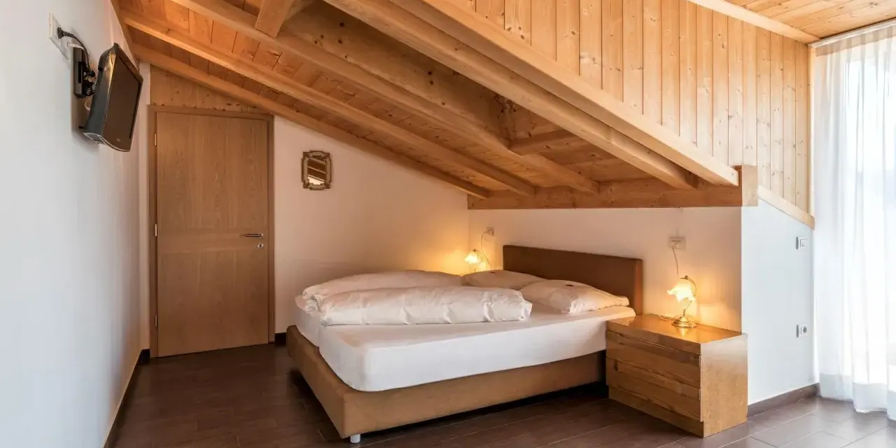 Camera accogliente con tetto in legno e letto matrimoniale. Un'oasi di pace all'hotel Weingarten Kaltern.