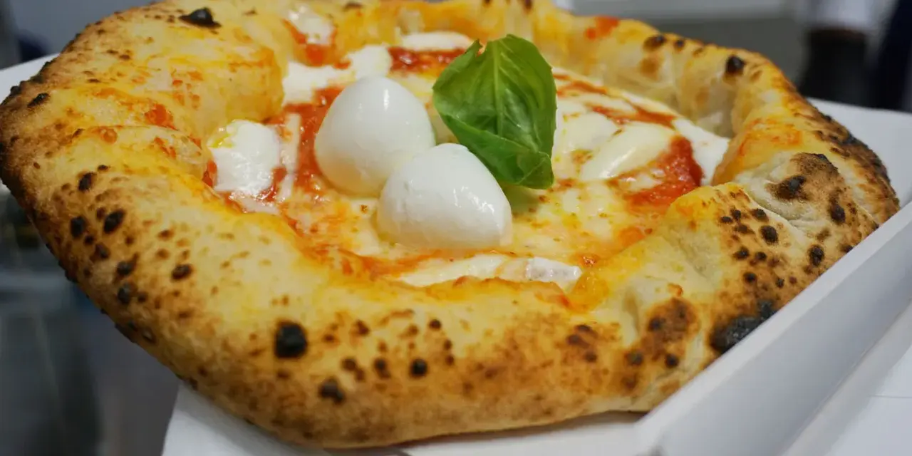 Pizza Margherita appena sfornata, con mozzarella di bufala e basilico fresco. Un vero assaggio di cibo napoletano.