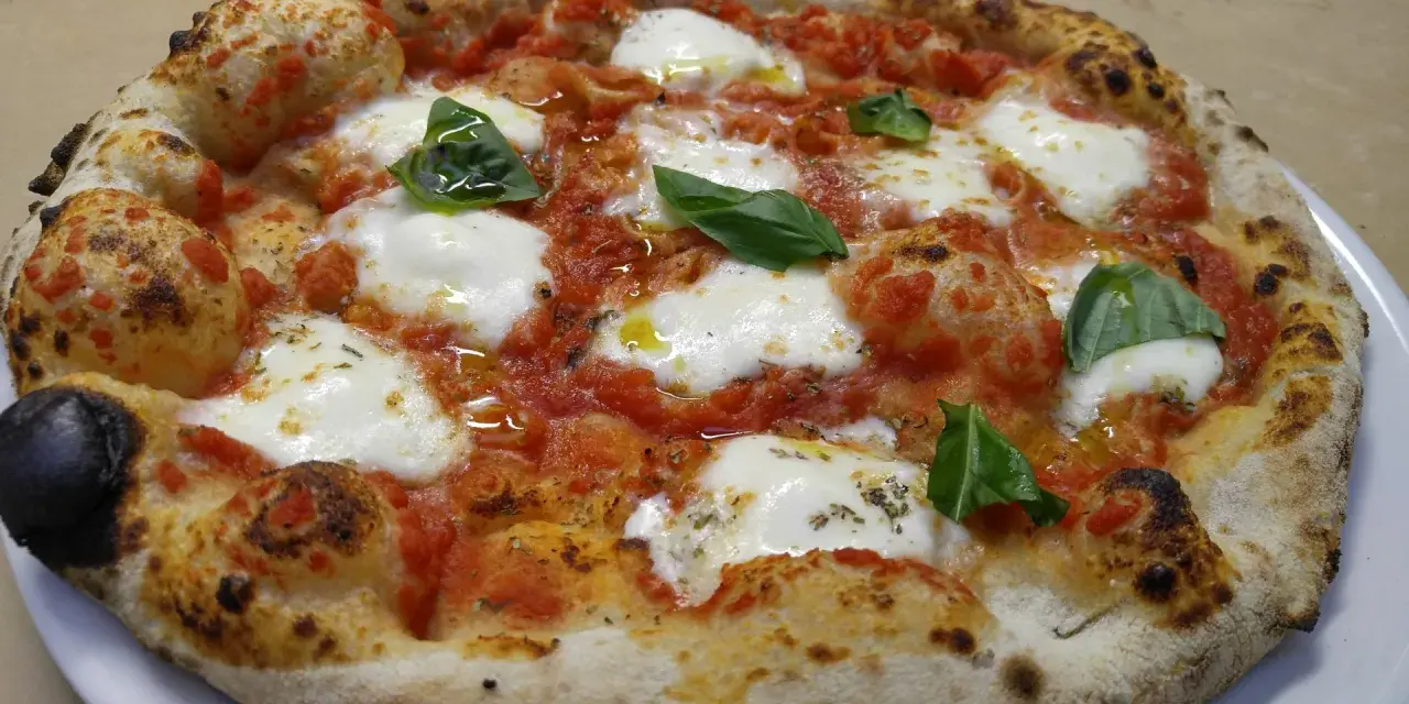 Pizza margherita con mozzarella filante, pomodoro e basilico fresco. Una vera casa matta, nota per la sua bontà.