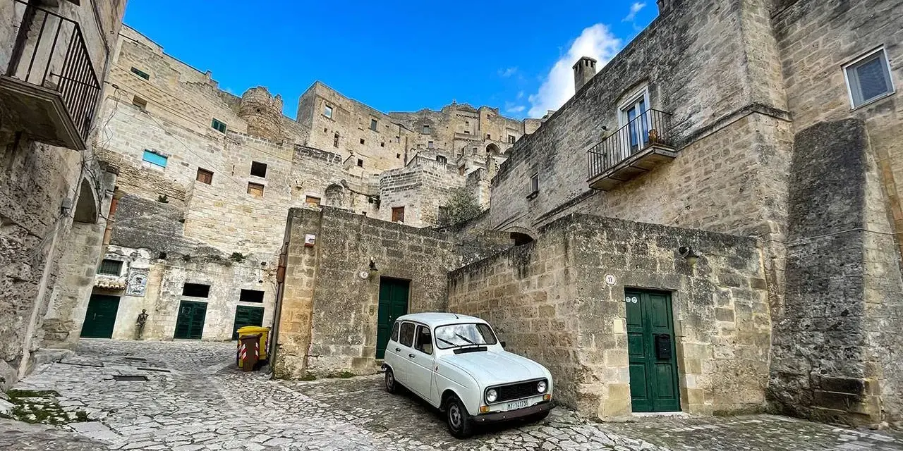 Un'auto d'epoca bianca in un vicolo di Matera, perfetta per visitare la città in un giorno.