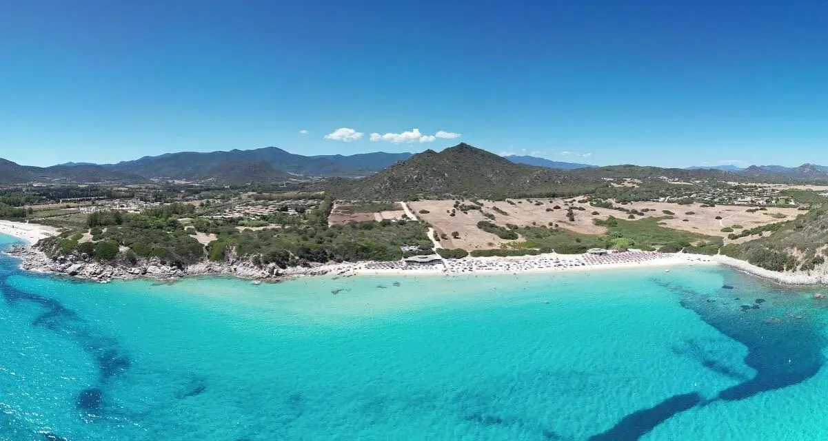 Spiaggia di Castiadas con acque cristalline e montagne sullo sfondo. Un luogo da sogno, quasi come vedere il delfino Castiadas nuotare felice.