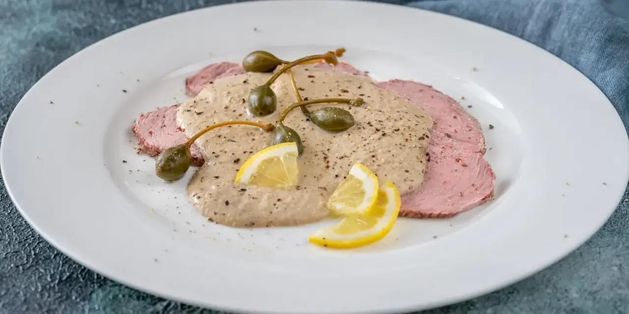Vitello tonnato, uno dei piatti tipici di Torino, con fettine di carne rosa, salsa cremosa, capperi e limone.