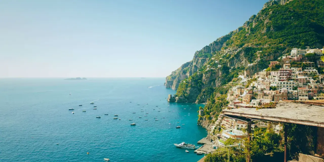 Positano, una delle perle delle regioni d'Italia, si affaccia sul mare blu con case colorate aggrappate alla scogliera.