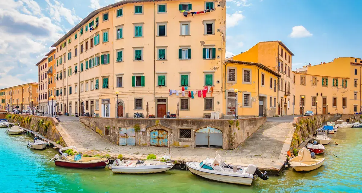 Canali di Livorno, cosa vedere in un giorno: case colorate affacciate sull'acqua, barche ormeggiate e panni stesi al sole.