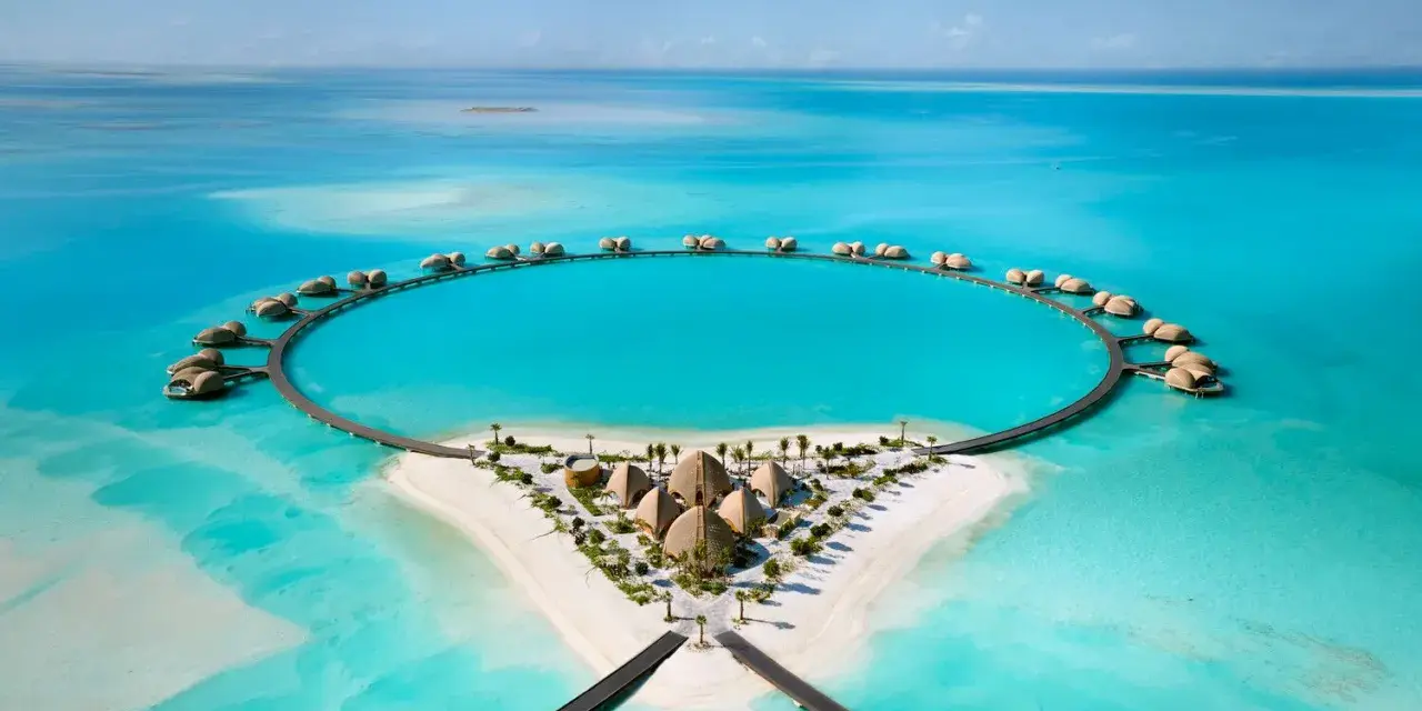 Resort circolare su un'isola tropicale, perfetto per le tue vacanze ad agosto. Case sull'acqua e sabbia bianca.